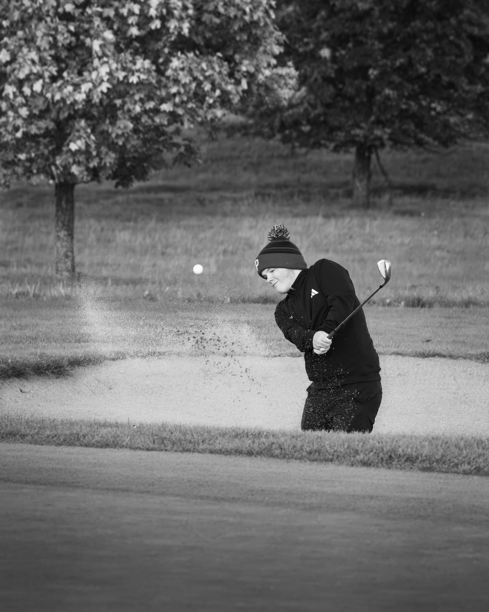 Black and white image of a golfer doing a bunker shot at St. Laurence Golf